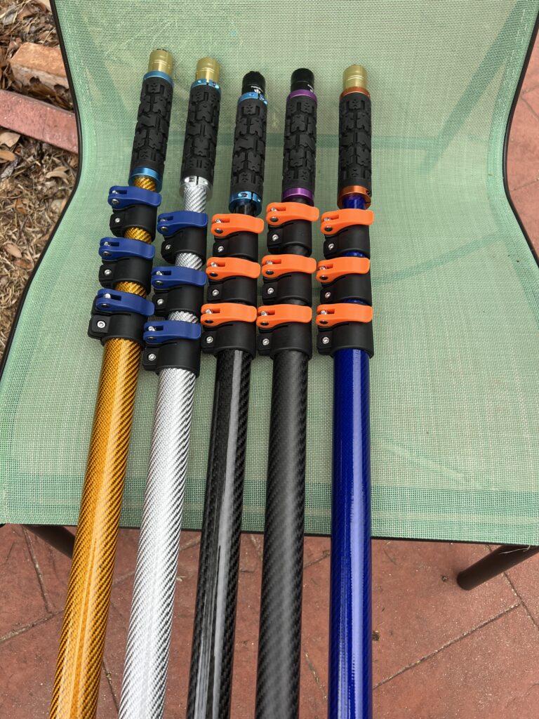 Five 26-foot carbon fiber pool poles with quick-release clamps, shown in gold, silver, glossy black, matte black, and blue finishes.